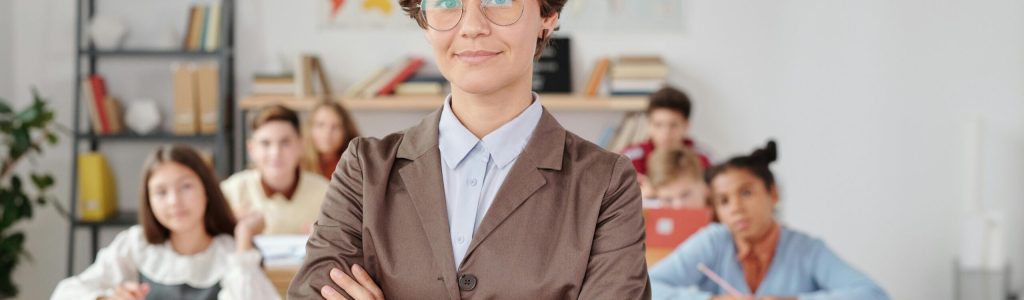 pexels-photo-5212682-5212682 A confident teacher stands in front of students in a classroom setting.